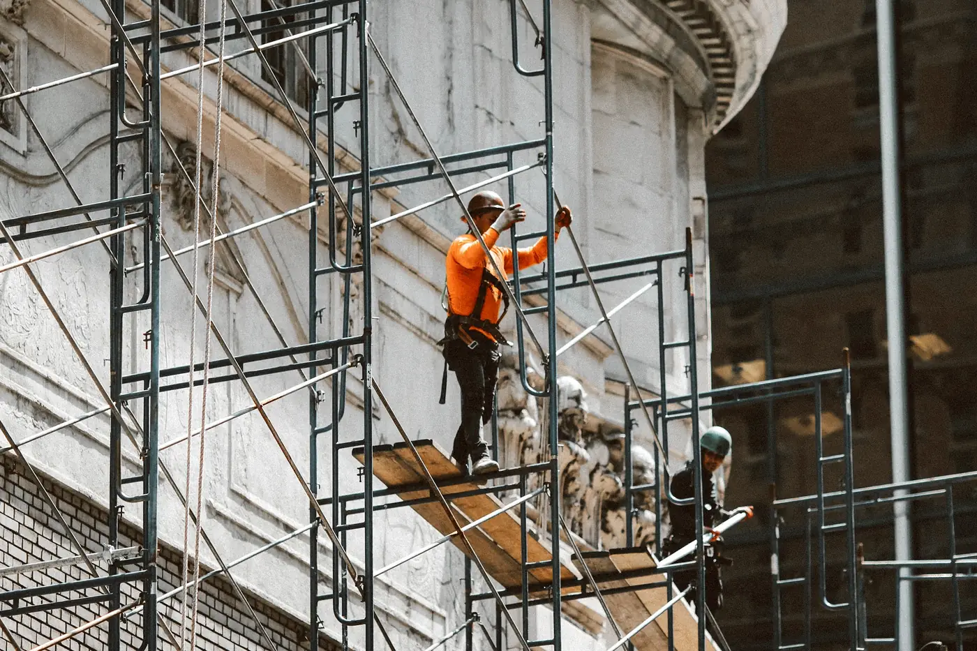 Ouvriers sur un échafaudage le long d’une façade ancienne en pierre sculptée