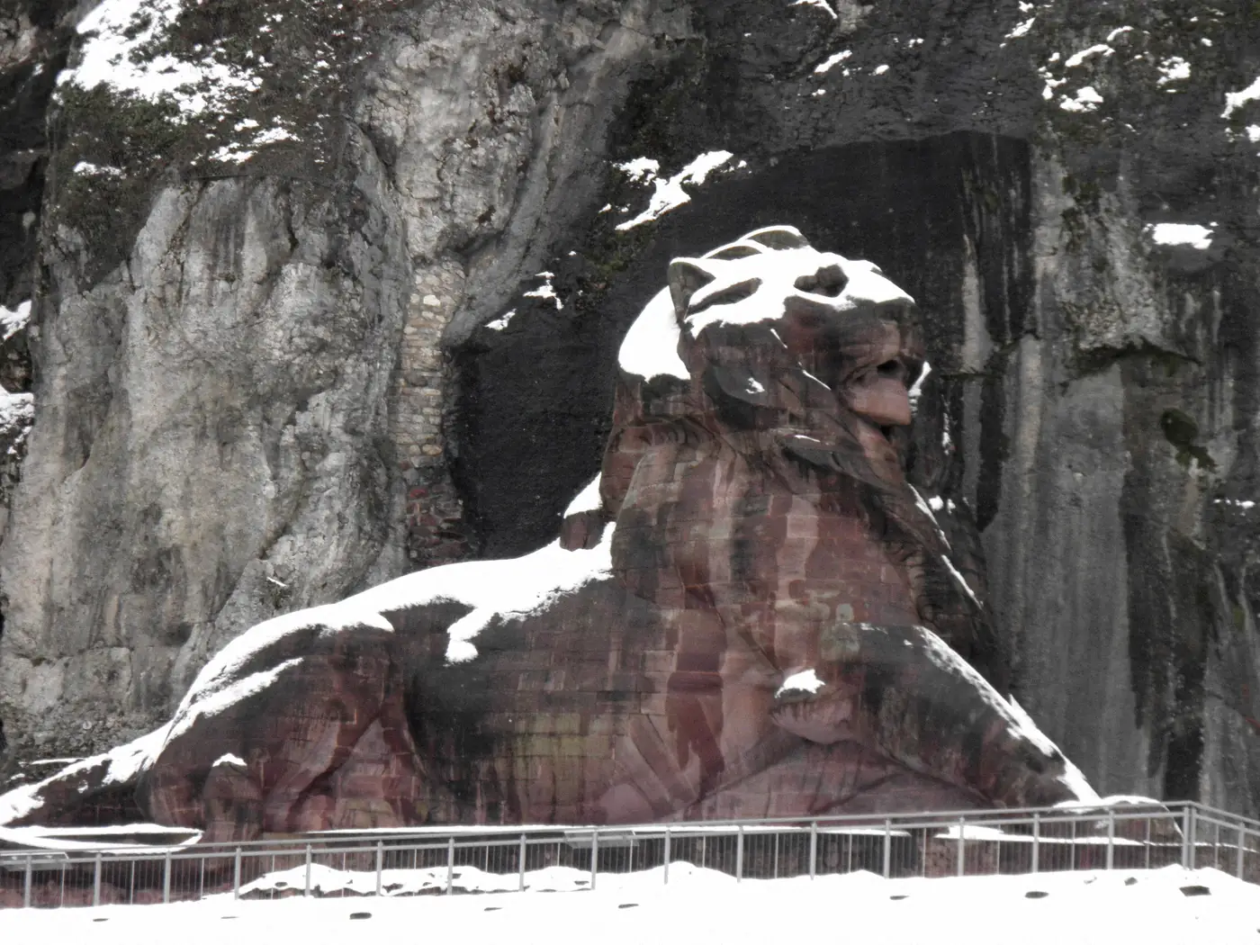 Le Lion de Belfort couvert de neige, adossé à la falaise grise de la citadelle